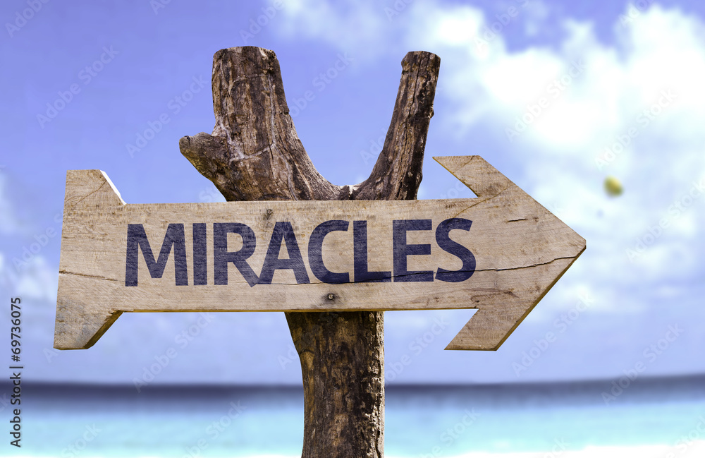 Miracles wooden sign with a beach on background