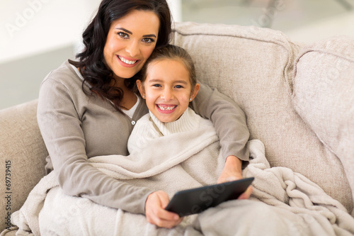 woman and her little daughter snuggle on couch