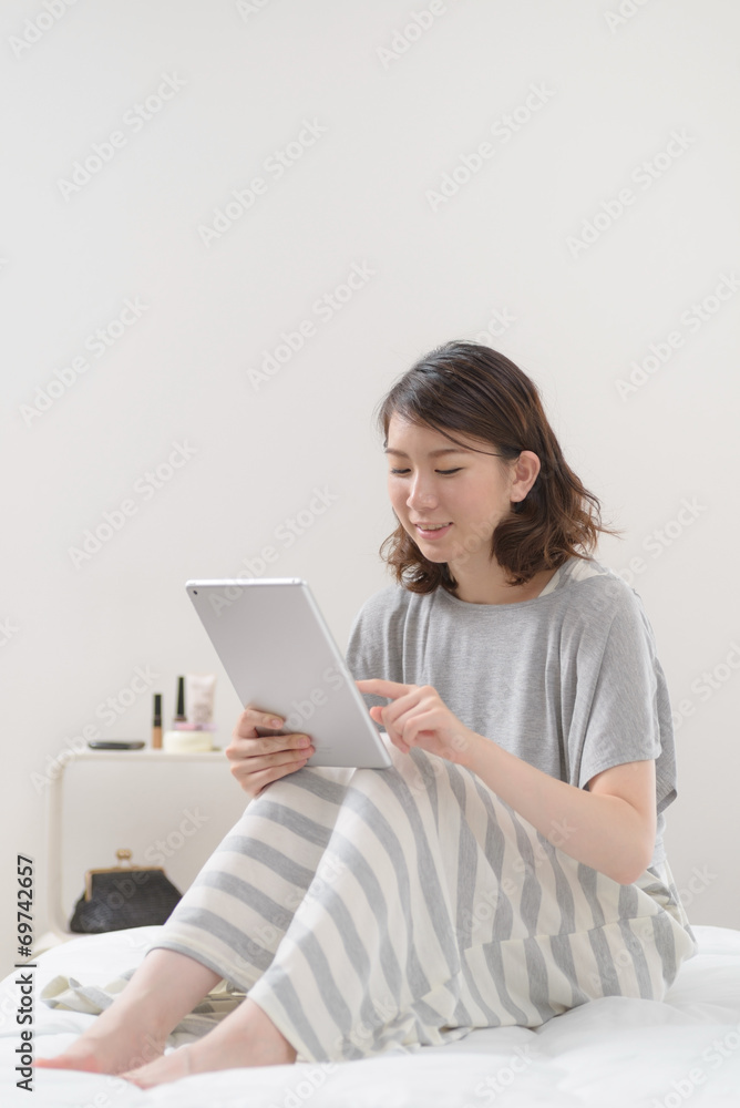 ベッドでタブレット端末を使う女性 ベッドでタブレット端末を使う女性