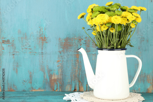 Fototapeta Naklejka Na Ścianę i Meble -  Yellow and green flowers in decorative teapot