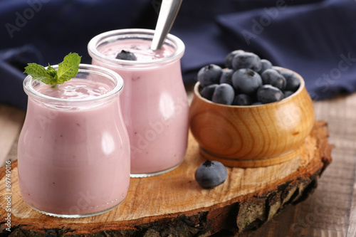 yogurt with blueberries in a glass jar and blueberries in a wood