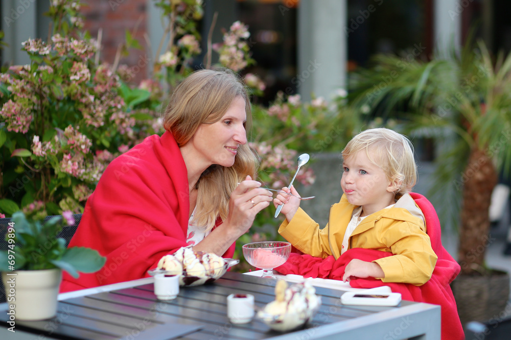 Mother and daughter eating ice cream in cafe Mother and daughter eating ice cream in cafe