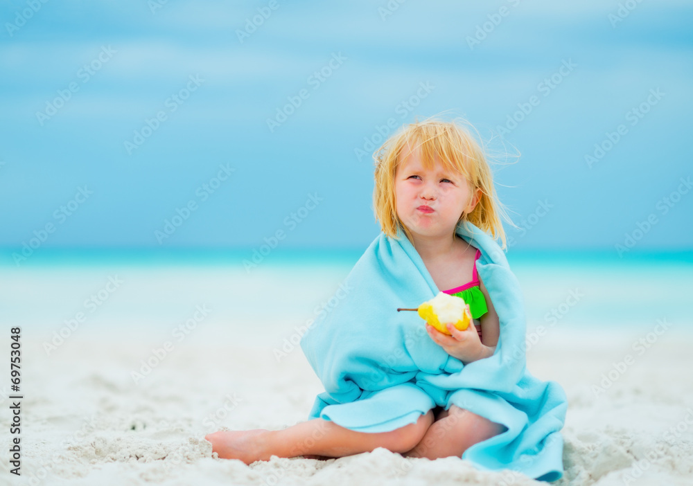 Portrait of baby girl eating pear on beach Portrait of baby girl eating pear on beach