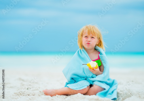 Portrait of baby girl eating pear on beach
