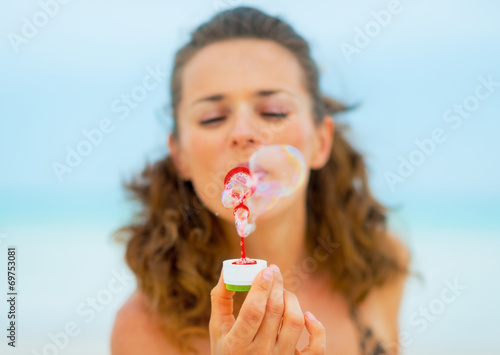 Closeup on young woman blowing soap bubbles on beach