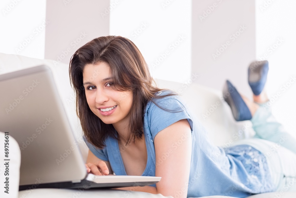 Pretty brunette using laptop on the couch Pretty brunette using laptop on the couch
