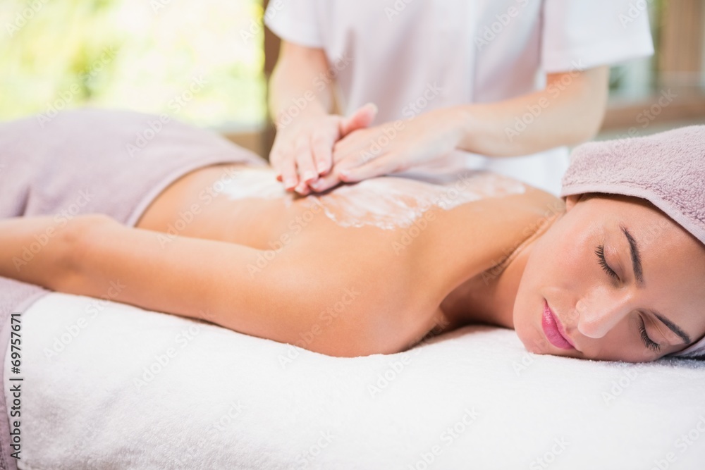 Attractive woman receiving back mask cream at spa center Attractive woman receiving back mask cream at spa center