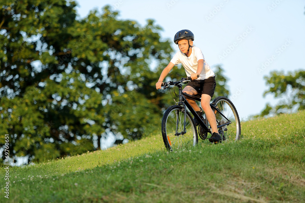 Teenage boy rides a bike from the hill in city park Teenage boy rides a bike from the hill in city park