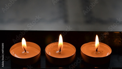 Three burning church candles on stand