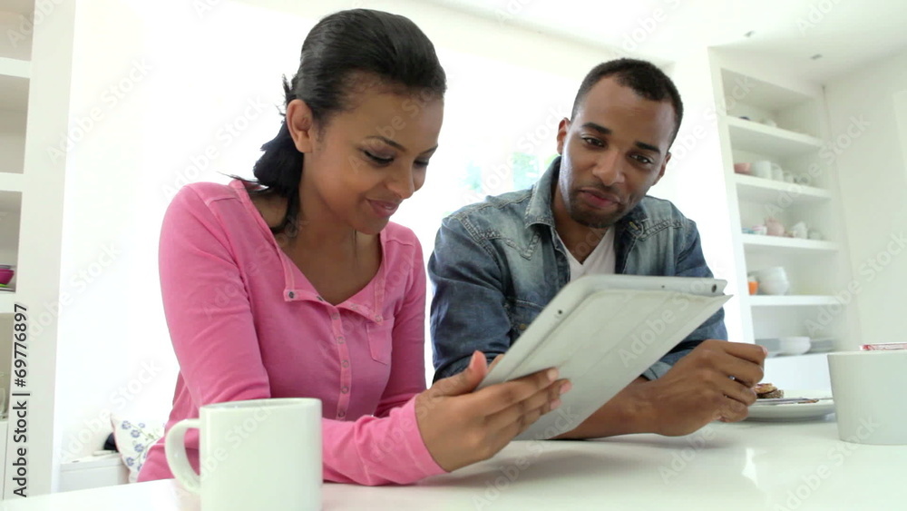 Couple Having Breakfast And Using Digital Tablet In Kitchen Couple Having Breakfast And Using Digital Tablet In Kitchen