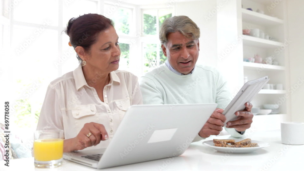 Senior Indian Couple Using Laptop And Digital Tablet At Home Senior Indian Couple Using Laptop And Digital Tablet At Home