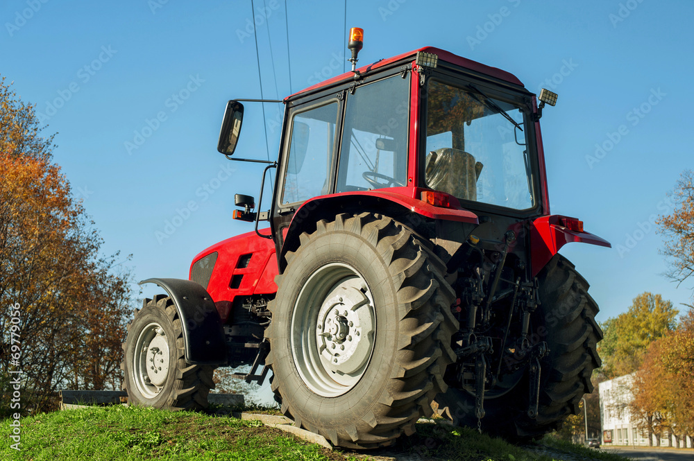 Modern red tractor on a blue sky background. Outdoors. Modern red tractor on a blue sky background. Outdoors.