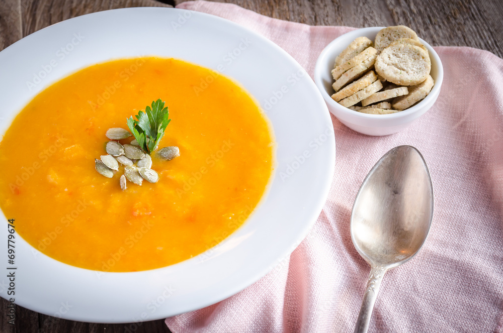 Portion of pumpkin cream soup on the wooden table Portion of pumpkin cream soup on the wooden table