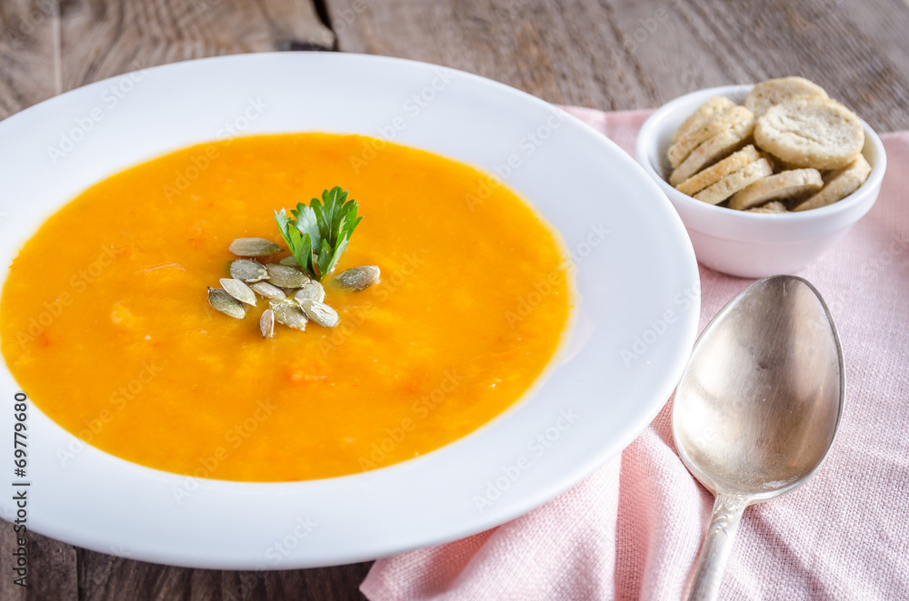Portion of pumpkin cream soup on the wooden table Portion of pumpkin cream soup on the wooden table