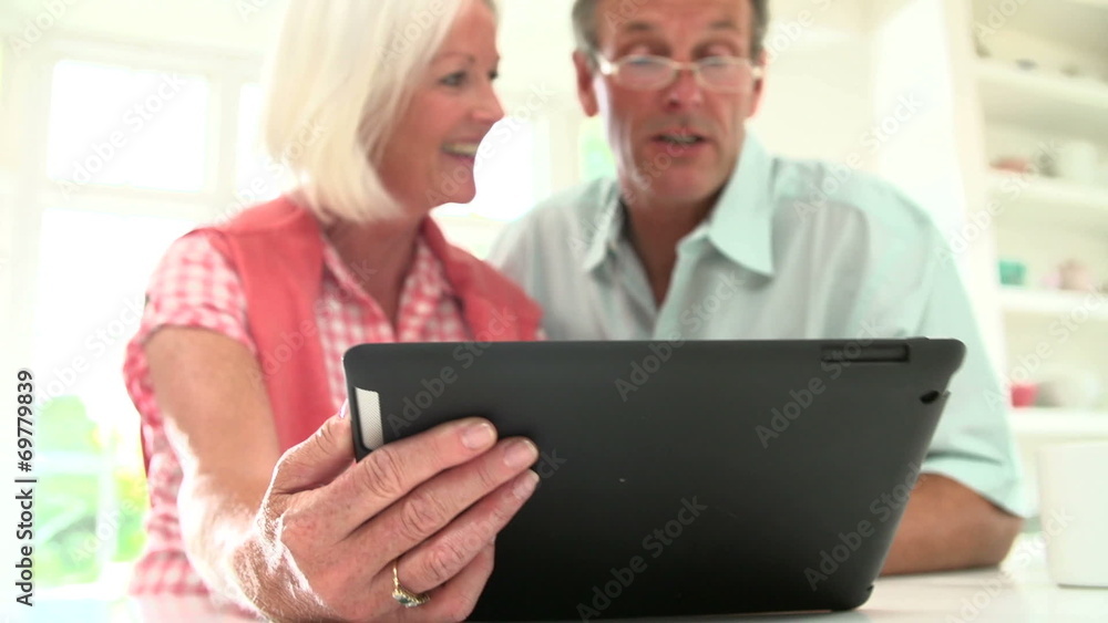 Middle Aged Couple Looking At Digital Tablet Middle Aged Couple Looking At Digital Tablet