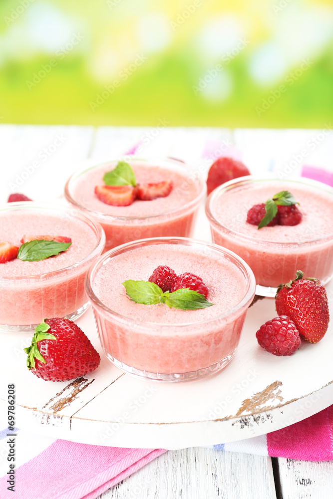 Delicious berry mousse in bowls on table on bright background