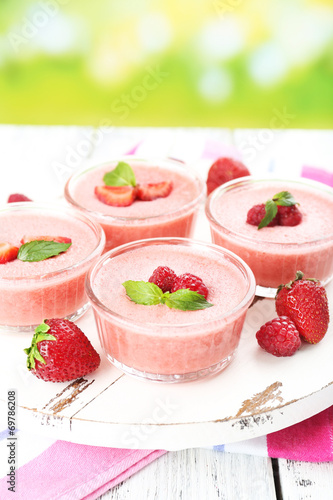Delicious berry mousse in bowls on table on bright background