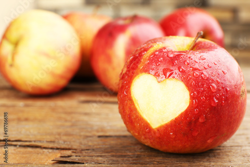 Red apple with heart on wooden table, close-up