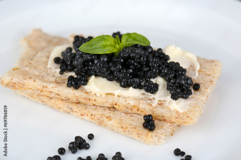 Slices of bread with butter and black caviar on plate closeup Slices of bread with butter and black caviar on plate closeup