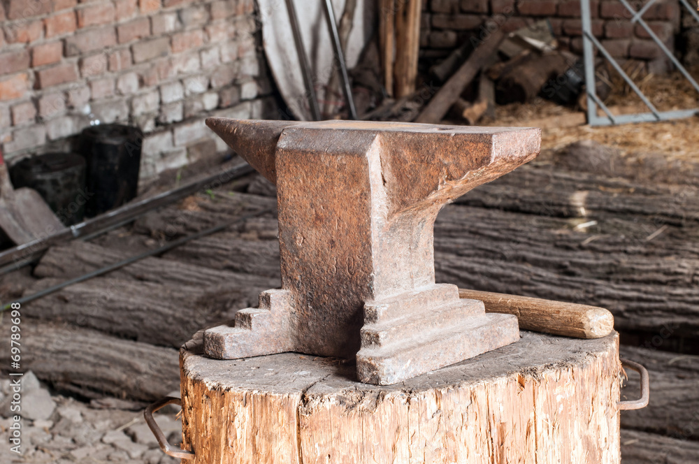 Rustic anvil on wooden stump.