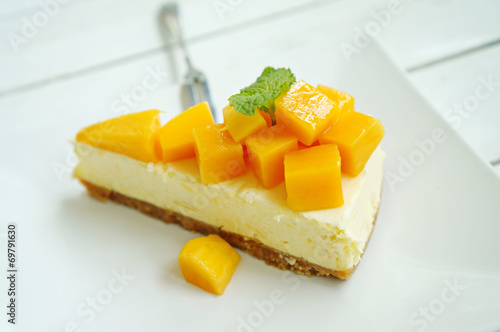 Mango cheesecake on white plate with fork