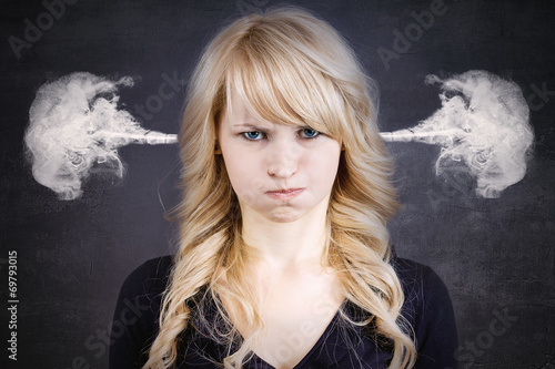 Angry young woman, blowing steam coming out of ears photo