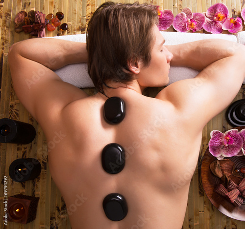 Man having stone massage in spa salon.