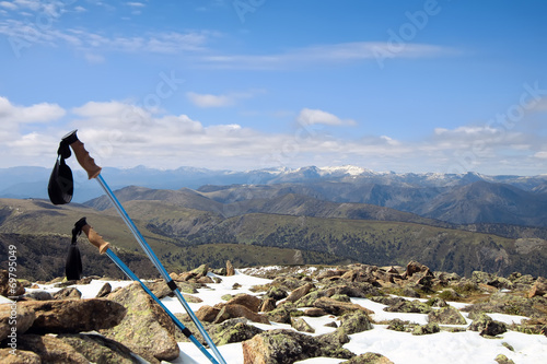 Trekking poles on a snowy summit of a mountain with a great view photo