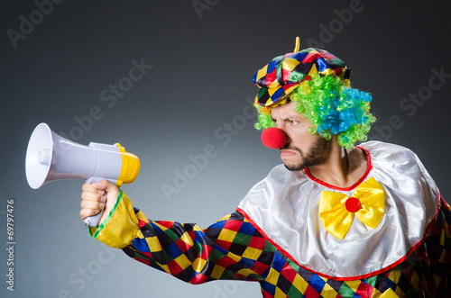 Clown with loudspealer against curtain