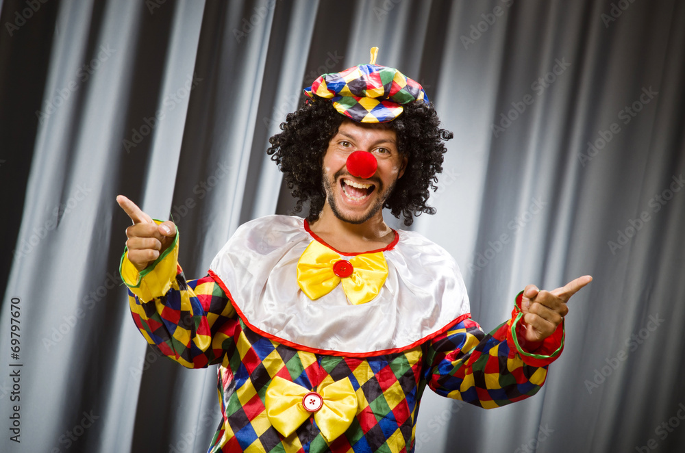 Funny clown in humorous concept against curtain Funny clown in humorous concept against curtain