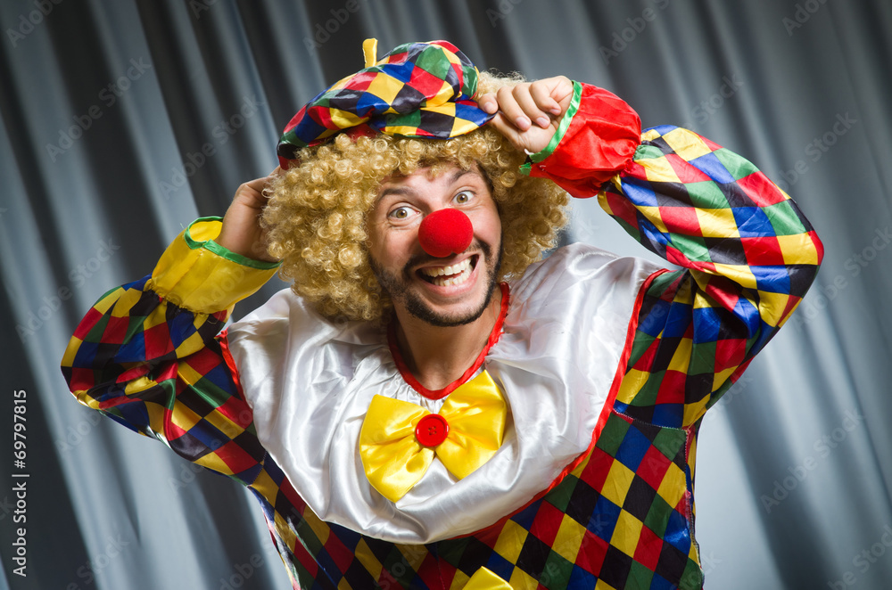 Funny clown in humorous concept against curtain Funny clown in humorous concept against curtain