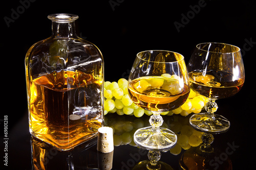 Bottle of brandy and two glasses and grapes photo