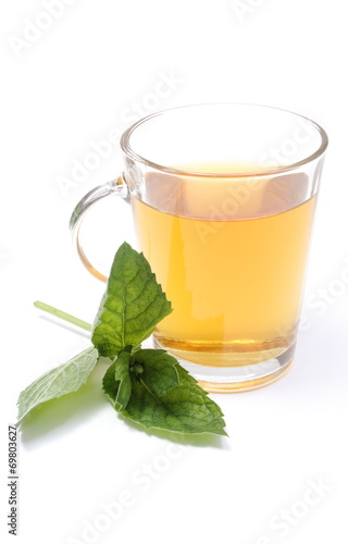 Fresh green mint and cup of beverage in background