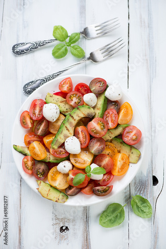 Vegetable salad with grilled avocado, white wooden background