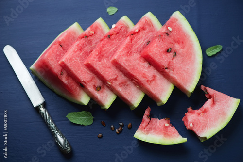 Sliced watermelon over dark blue wooden background, above view