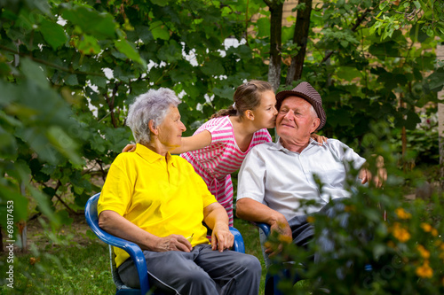 Grandparents and granddaughter  sitting outside © Mediteraneo