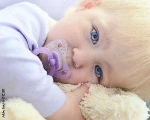 Obraz na płótnie Cute baby with blue eyes hugging a mascot. w salonie
