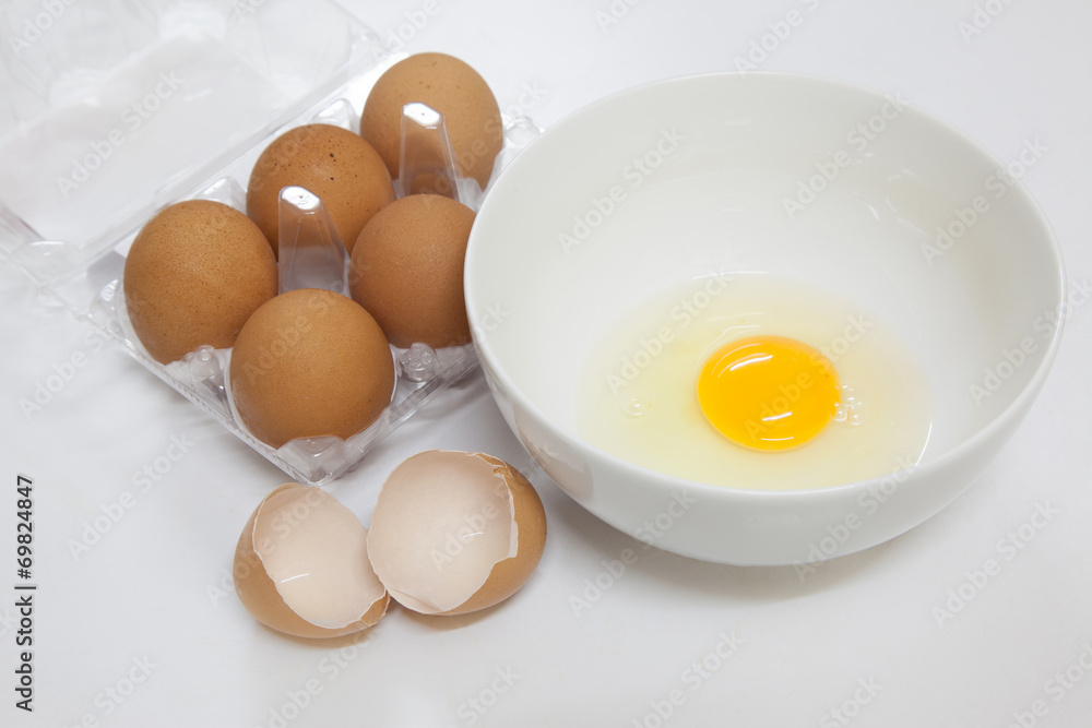 one egg yolk in white bowl and broken egg shells one egg yolk in white bowl and broken egg shells