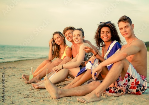 Group of multi ethnic friends with drinks relaxing on a beach © Nejron Photo