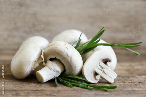 Champignon mushrooms on wooden board with spice branch