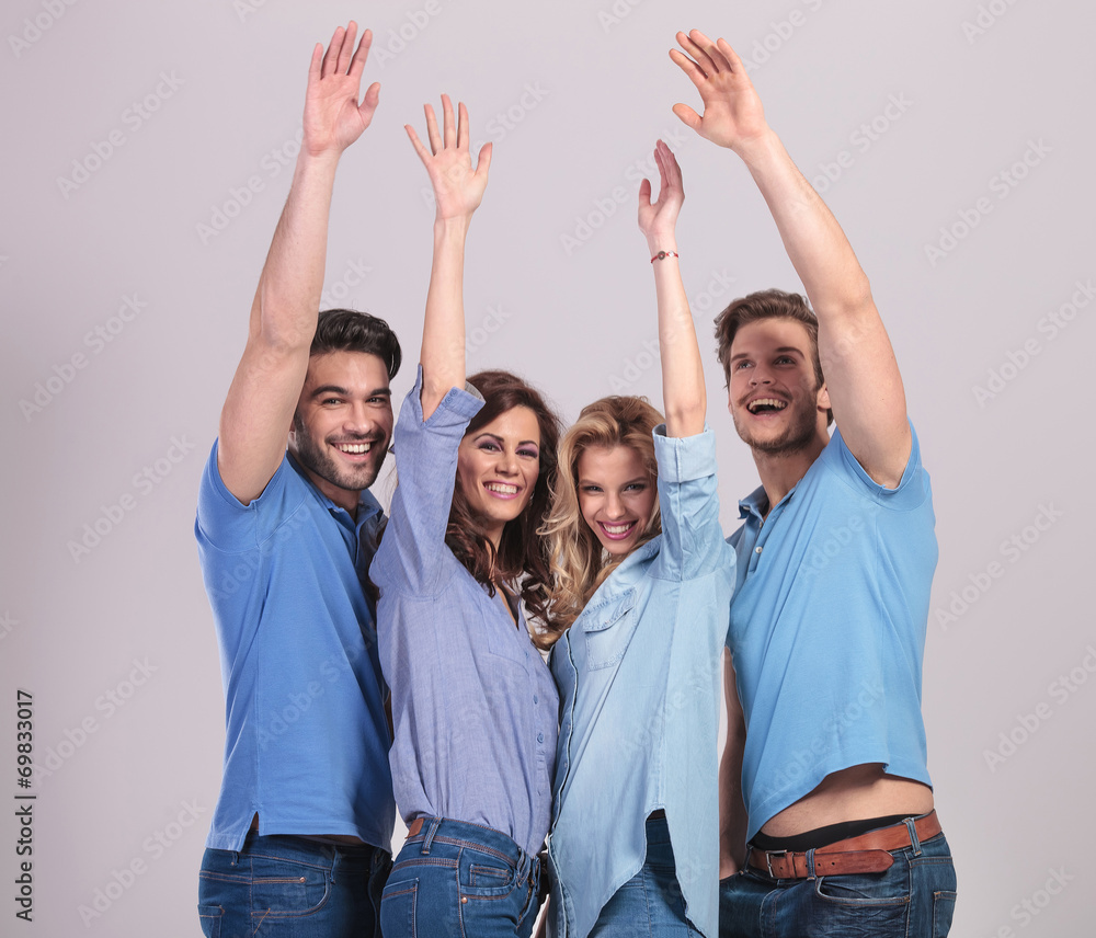 happy group of young people celebrating success with hands raise