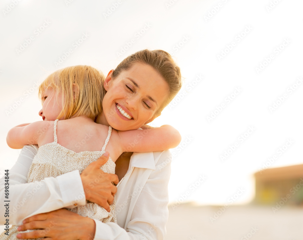 Portrait of mother and baby girl hugging on the beach Portrait of mother and baby girl hugging on the beach