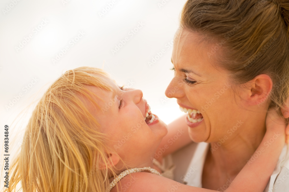 Portrait of smiling mother and baby girl hugging on the beach Portrait of smiling mother and baby girl hugging on the beach