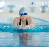 Young girl in goggles swimming breaststroke stroke style