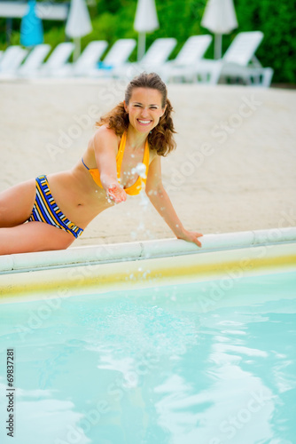 Portrait of happy woman playing with water in swimming pool
