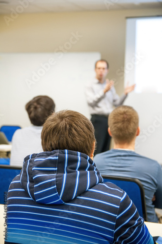 rear view of students in the class listening teacher explanation