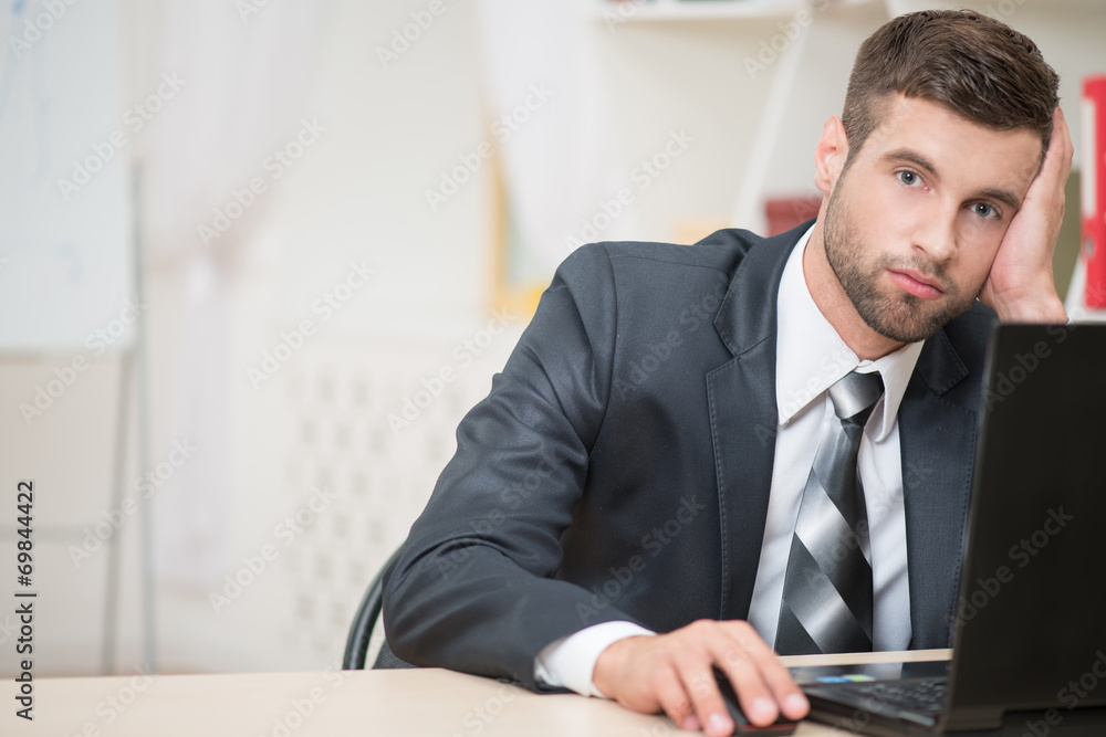 Businessman sitting at the table and working with laptop in offi Businessman sitting at the table and working with laptop in offi