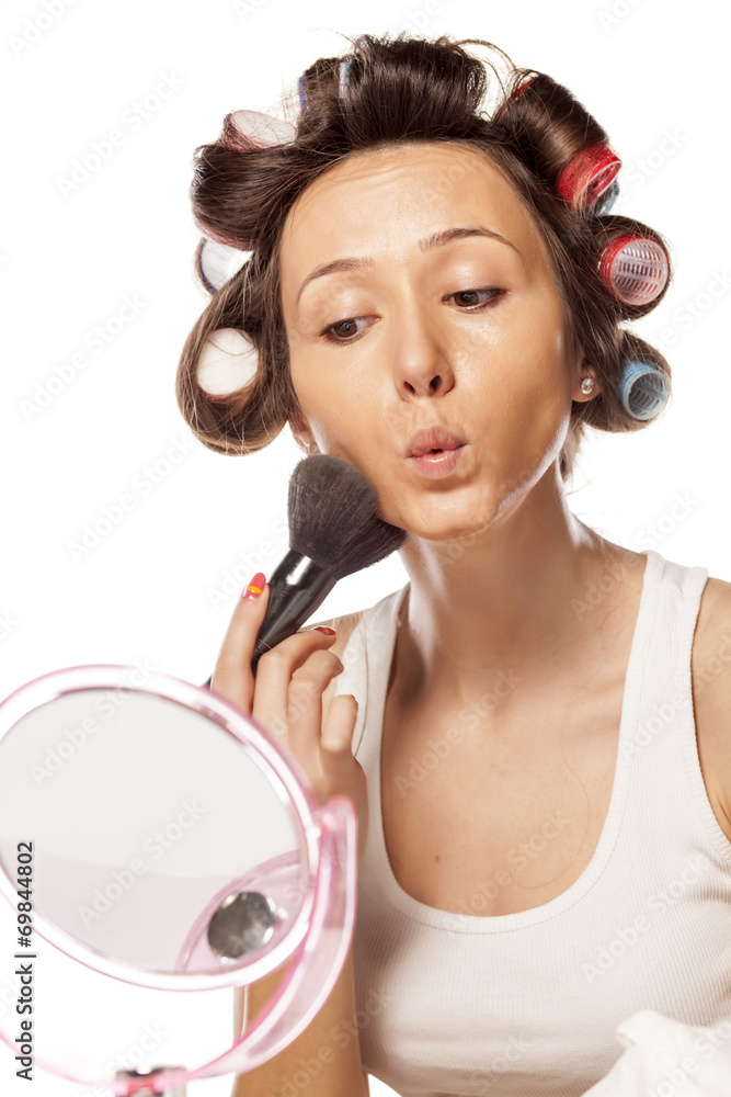 happy housewife with curlers to apply makeup on her face happy housewife with curlers to apply makeup on her face