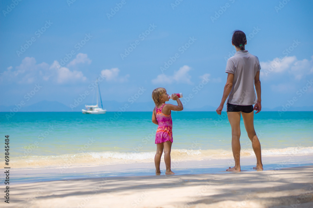 Adorabel daughter and father on sand beach of ocean. Girl drinki