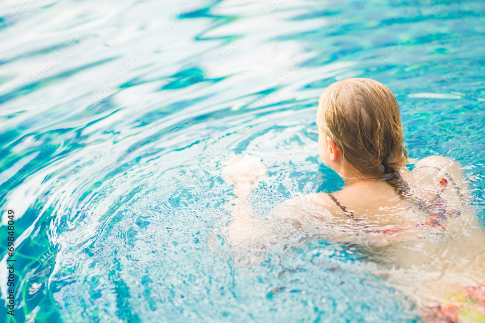 Young woman start to swim in tropical beach resort pool